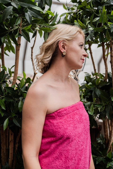 1. Woman wearing RÄTT fuchsia cotton terry spa wrap, standing in a garden setting