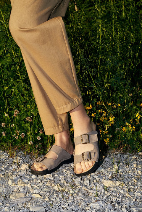 4. Close-up of Omaking Meeliku grey leather sandals worn by a woman, showing adjustable buckle straps and natural leather insole
