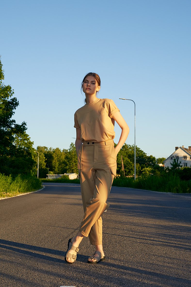 1. Woman wearing Omaking Meeliku grey leather sandals with adjustable buckle straps, standing on a road in a casual outdoor setting