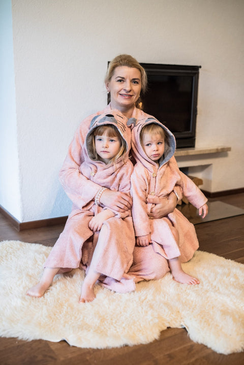 4. Two toddlers in pink RÄTT Bamboo Terry Bathrobe CAT with hood, sitting with adult