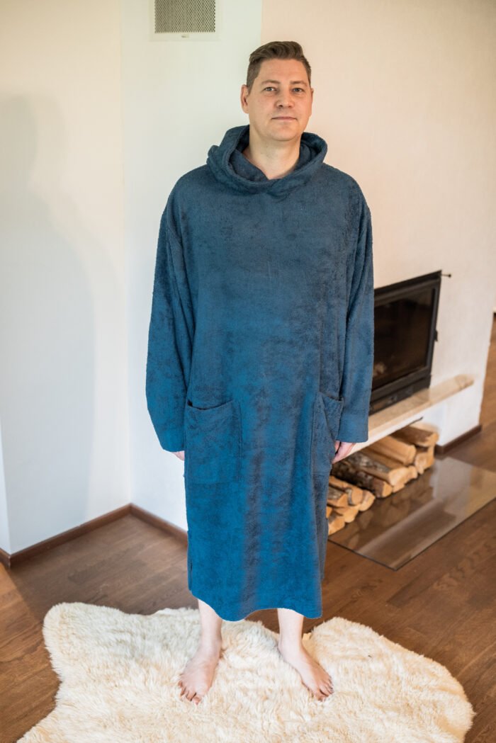 9. Men's blue bamboo terry long-sleeve poncho with hood, worn by model standing indoors on a rug