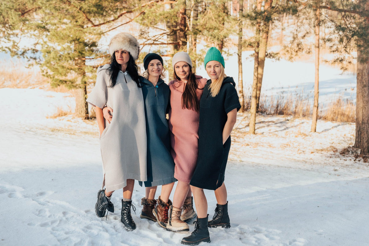 1. Group of women wearing RÄTT short-sleeve surf ponchos in various colors, standing in snowy landscape