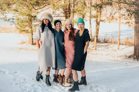 1. Group of women wearing RÄTT short-sleeve surf ponchos in various colors, standing in snowy landscape