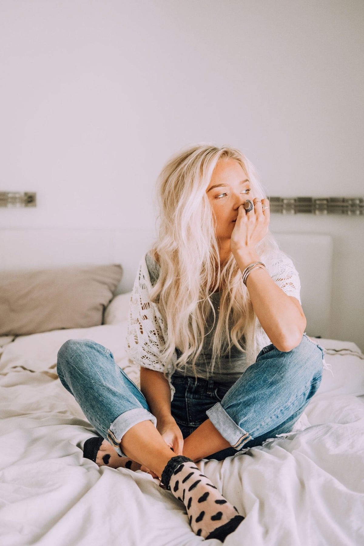 3. Woman sitting on bed wearing Olla SEURAA UNELMIASI bracelet, showcasing casual style