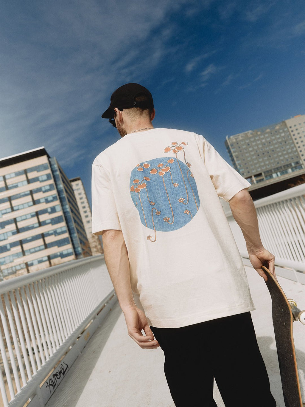 5. Men's heavy-weight premium t-shirt 'Bijutsu Sekai' by Watanabe Seitei, worn by male model with skateboard, showcasing vine illustration, lifestyle setting