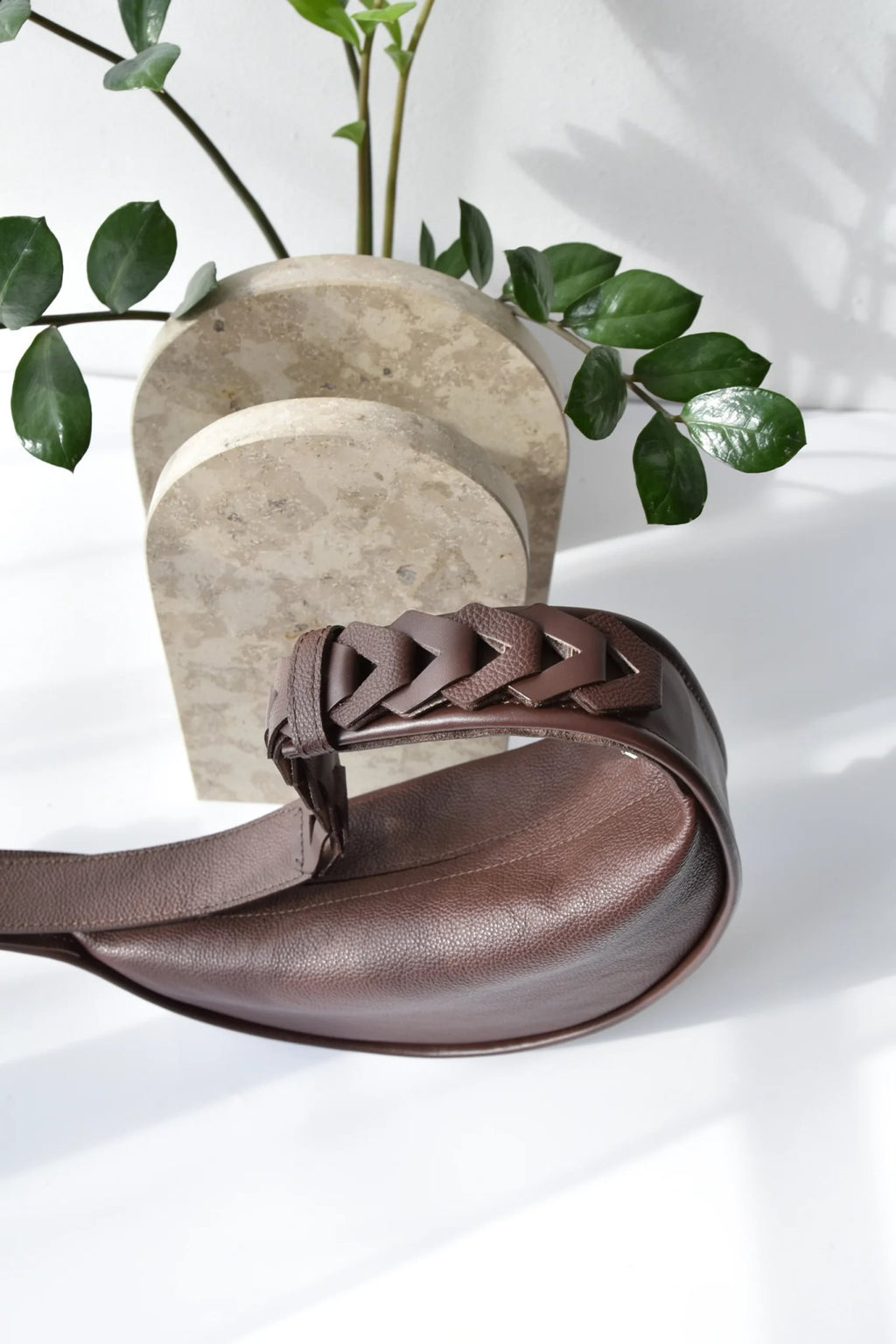 3. Dark brown Flora Leather Bag by Gerda Retter Design with braided strap, styled with greenery in studio