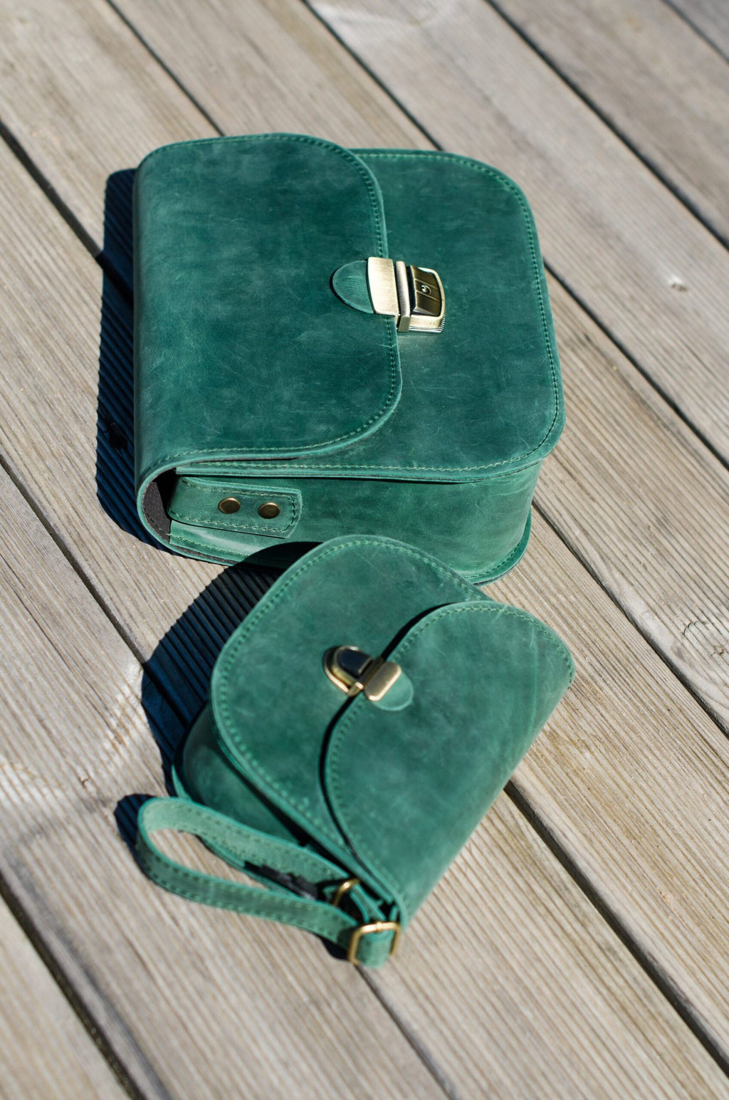 7. Zelma Kraft green leather saddle bag and smaller pouch on wooden surface, highlighting design and color