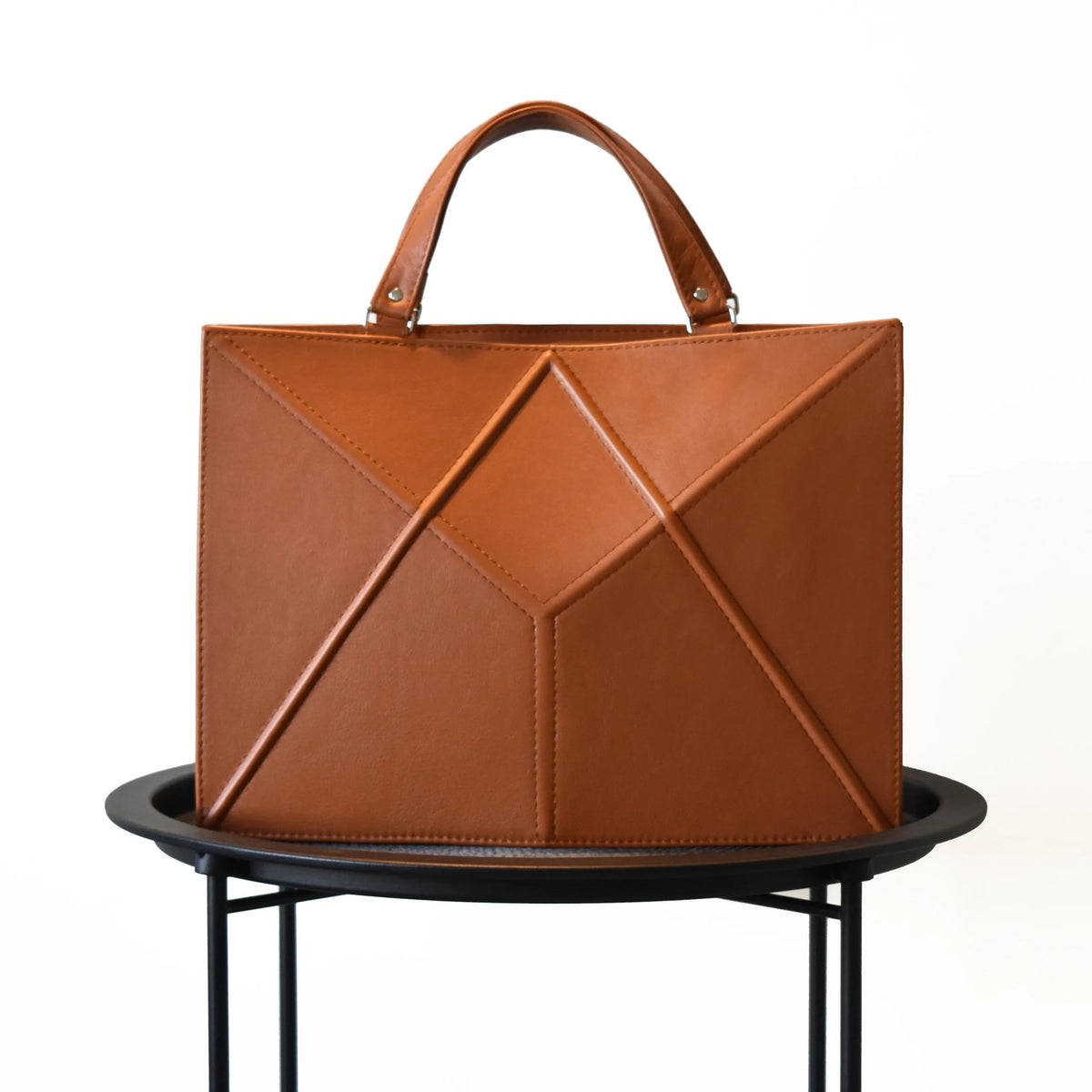 2. Front view of Gerda Retter Design FACET handbag in caramel brown, showcasing geometric design, studio setting