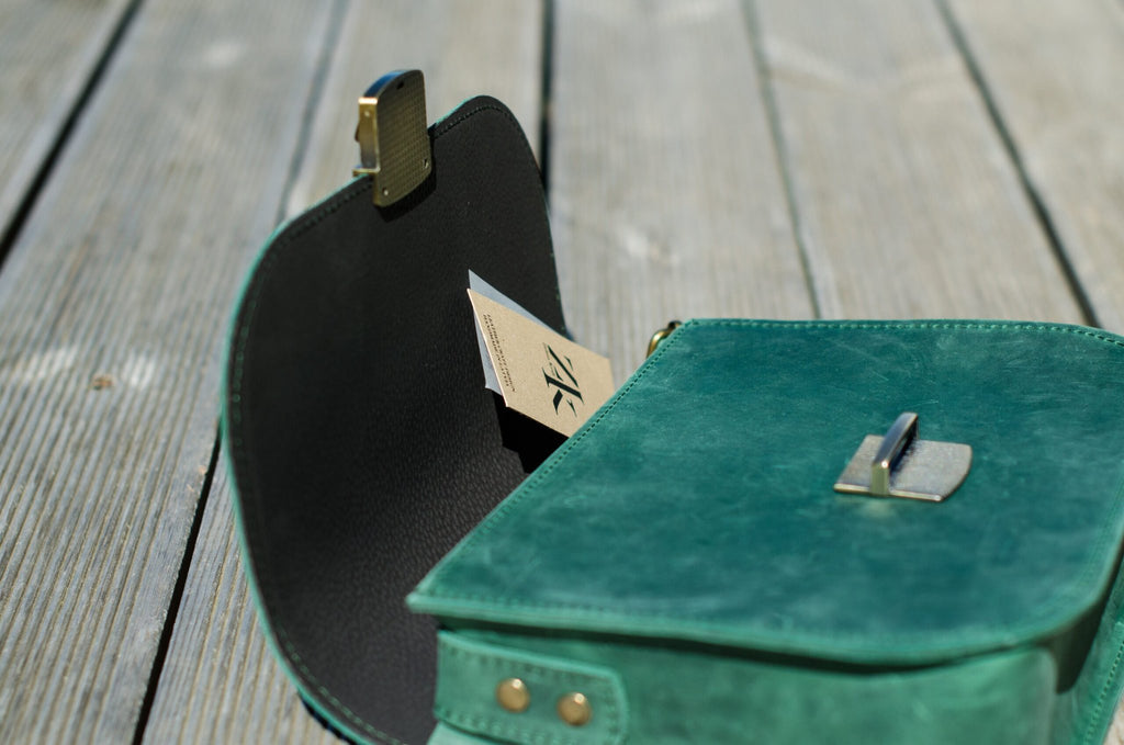 6. Close-up of Zelma Kraft green leather saddle bag open, showing interior and buckle detail