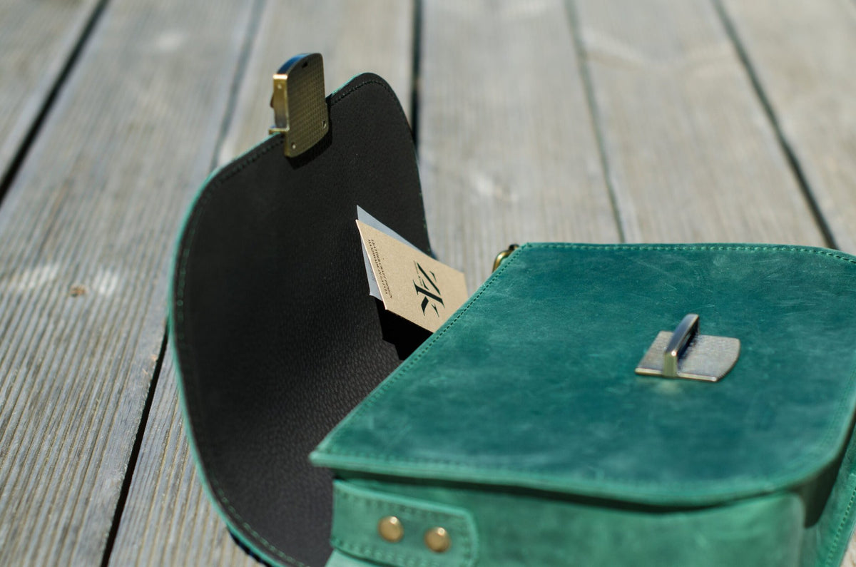 6. Close-up of Zelma Kraft green leather saddle bag open, showing interior and buckle detail