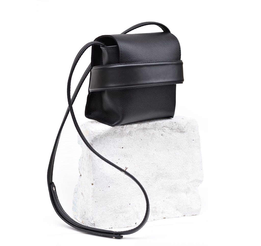3. Studio shot of black Luce shoulder bag by Gerda Retter Design with long strap, displayed on white block