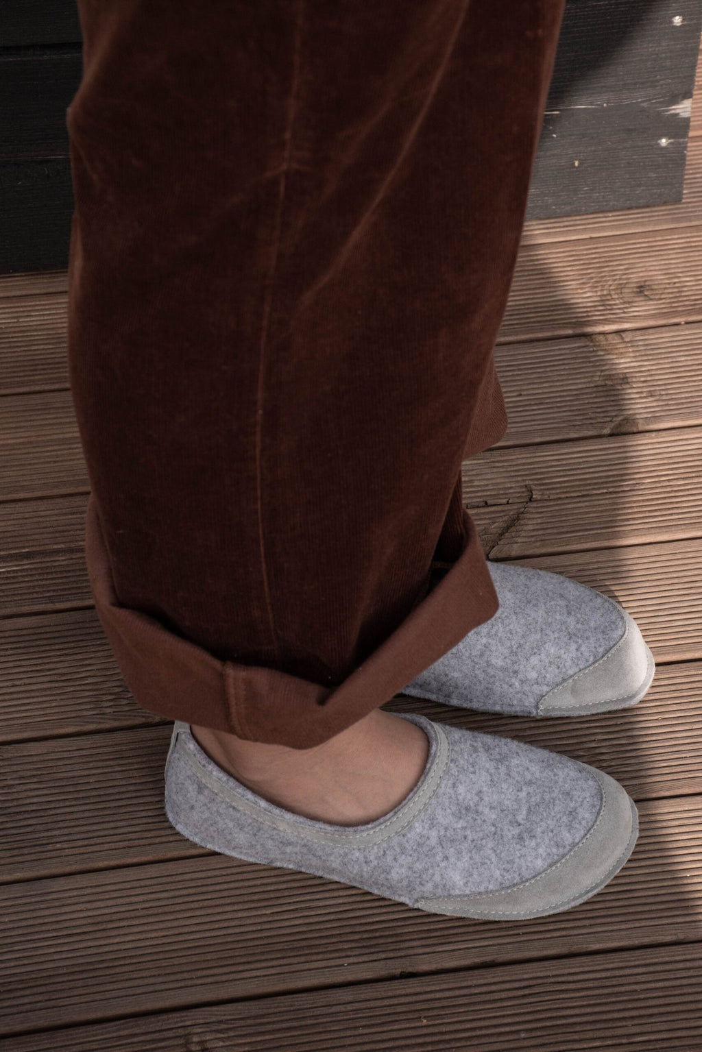 6. Unisex gray felt barefoot indoor slippers by Omaking worn by a model on wooden deck