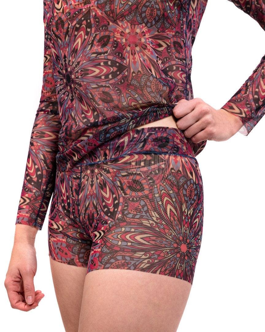 3. Back view of women's tan-through mini leggings and blouse set in terracotta mandala pattern, studio setting