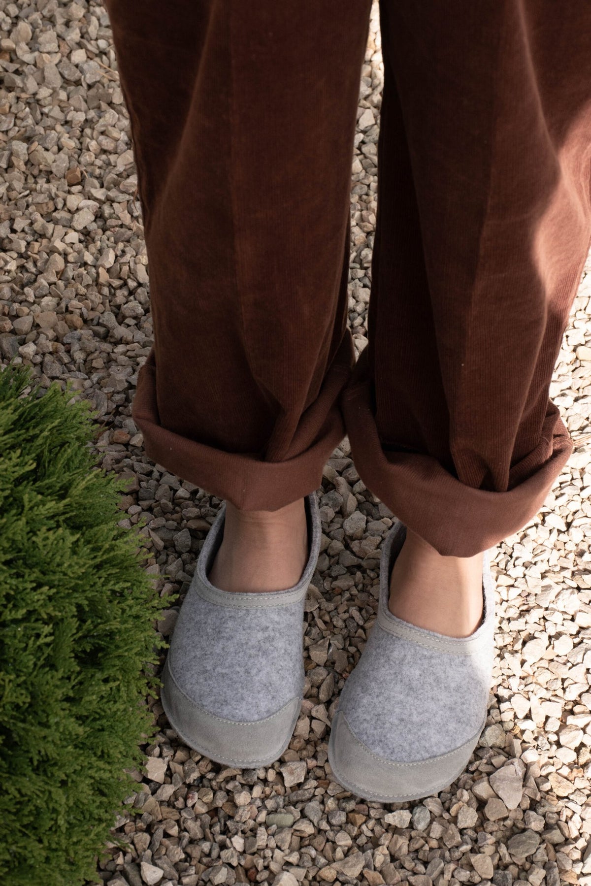 1. Unisex gray felt barefoot indoor slippers by Omaking worn by a model on gravel path