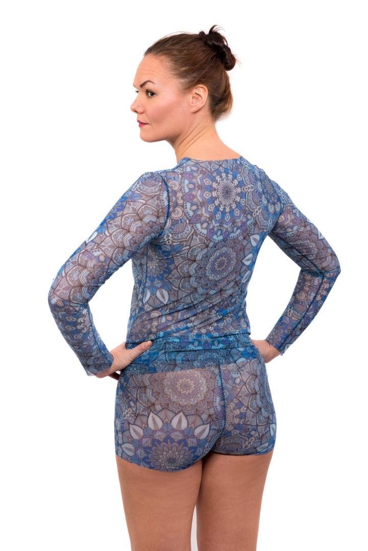 3. Woman wearing Smarttan's Tan-Through Mini Leggings in Blue Mandala, shown from the back in a studio setting