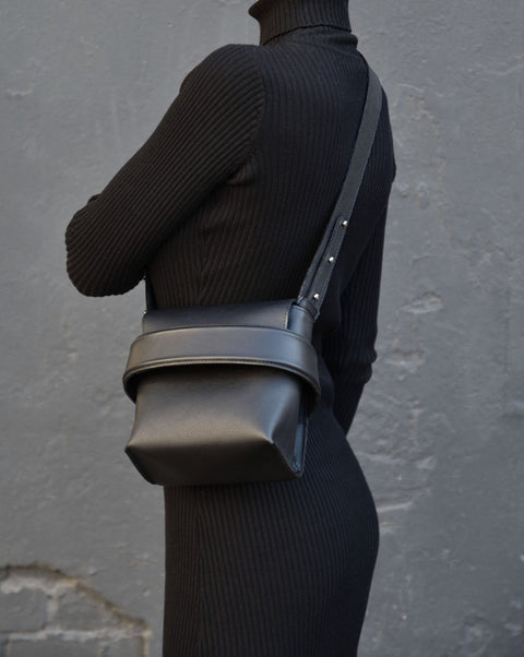 1. Women's black Luce shoulder bag by Gerda Retter Design worn crossbody with adjustable strap, shown in lifestyle setting