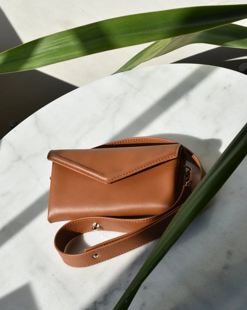 10. Closed brown Gerda Retter bag with adjustable strap on marble surface