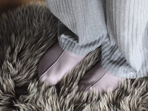 1. Lifestyle image of Sulbi Slippers in lilac worn by a person on a furry rug, showcasing comfort and style