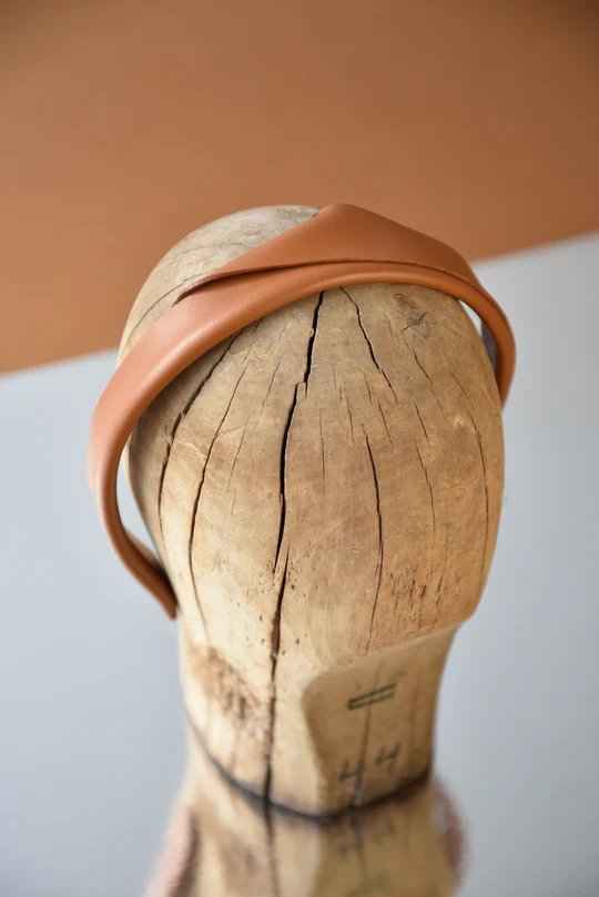 3. Caramel brown handmade leather headband by Gerda Retter Design, displayed on wooden mannequin head