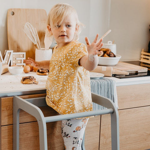 3. Child in yellow top on grey Montessori helper tower step stool in kitchen