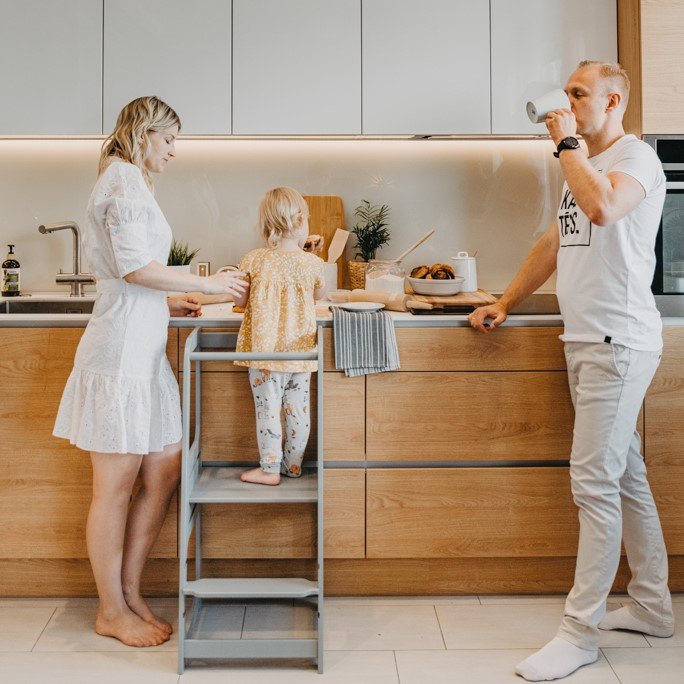 2. Family in kitchen with child on grey Montessori helper tower step stool