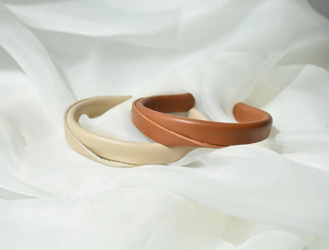 2. Close-up of beige and caramel brown handmade leather bracelets by Gerda Retter Design on white fabric, highlighting geometric elegance