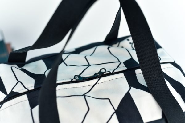 3. Close-up of Garbanota Travel Bag White Lion showing black and white geometric pattern and zipper detail