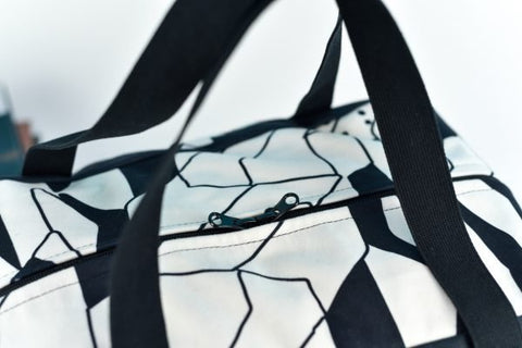 3. Close-up of Garbanota Travel Bag White Lion showing black and white geometric pattern and zipper detail