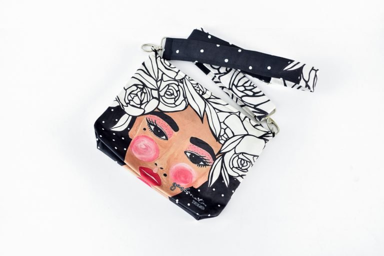 8. Garbanota YOKO makeup bag in black with colorful face illustration and floral design, featuring metal rings and strap