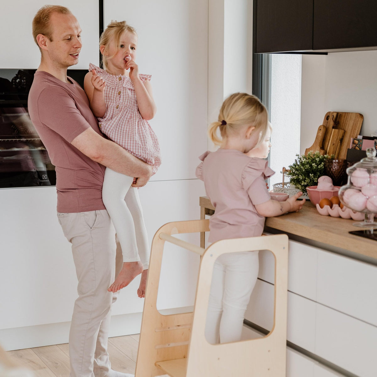 7. Family in kitchen with children using natural wood Montessori helper tower step stool