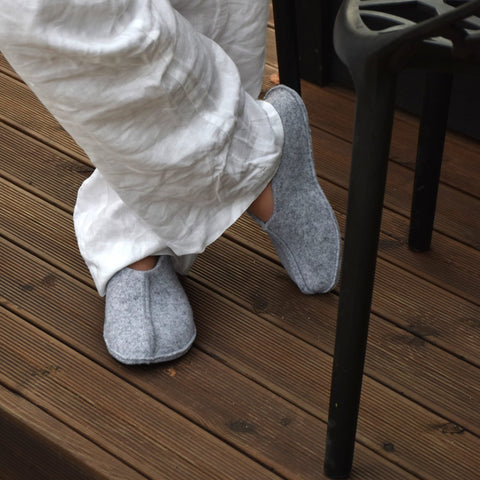 1. Unisex grey Tohkri slippers by Omaking worn by a person on a wooden deck, showcasing comfort and style