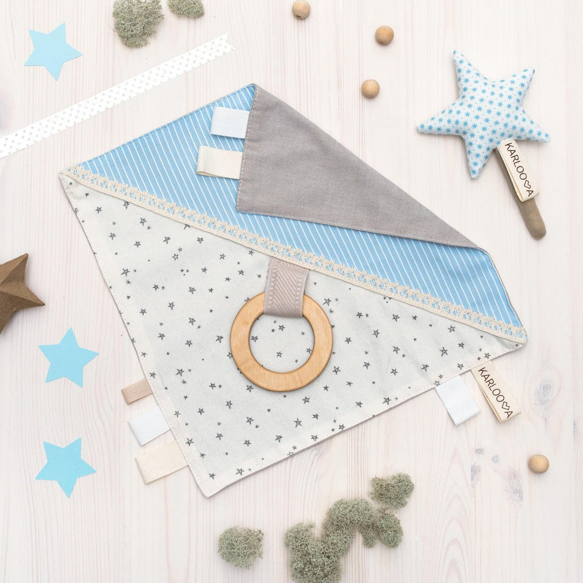 4. Flat lay of Karloova comfort blanket with blue and grey fabric, wooden grabbing hoop, and star pattern on light wooden background