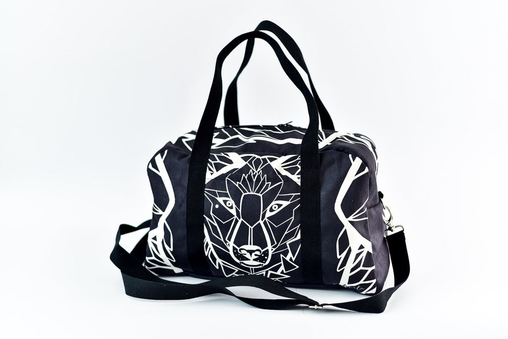 1. Garbanota Travel Bag White Wolf in black with geometric wolf design, featuring long strap and handles, studio setting