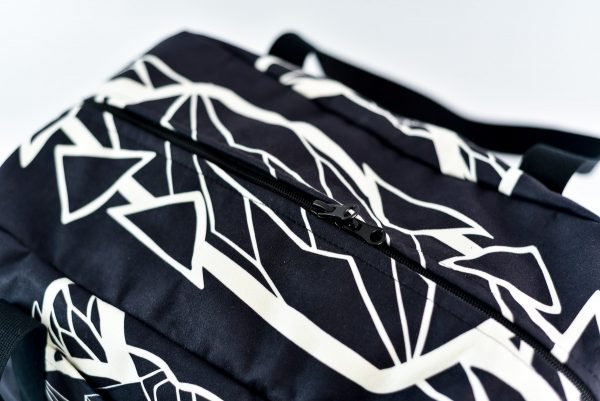 2. Close-up of Garbanota Travel Bag White Wolf in black, highlighting zipper and geometric pattern