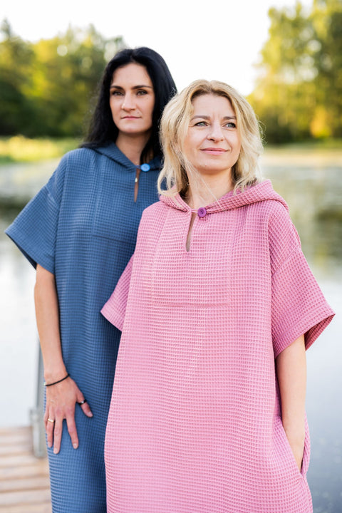 3. Two women in pink and blue RÄTT short-sleeve surf ponchos standing by a lake