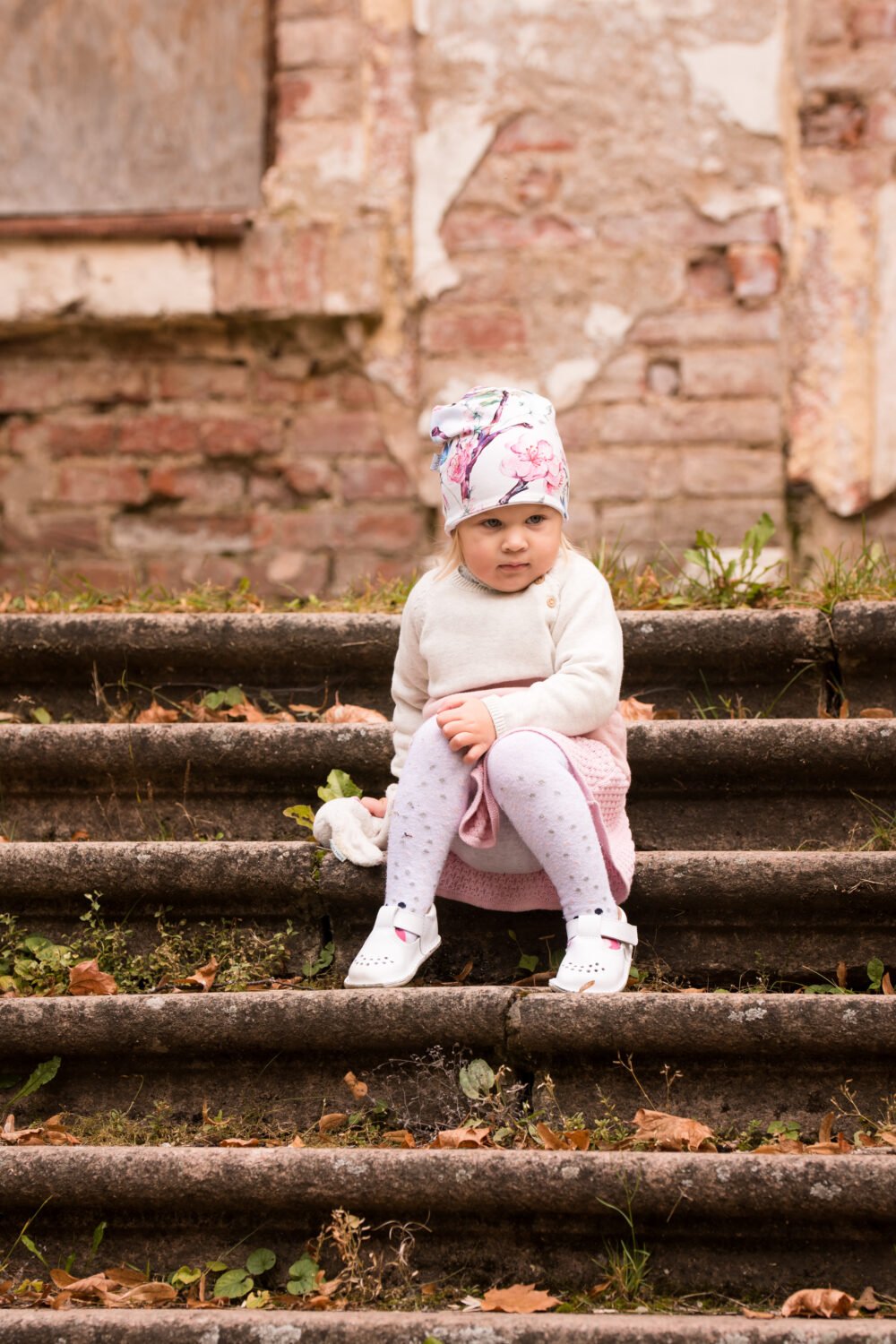 1. Child wearing Omaking Lusti white leather kids' shoes sitting on steps outdoors