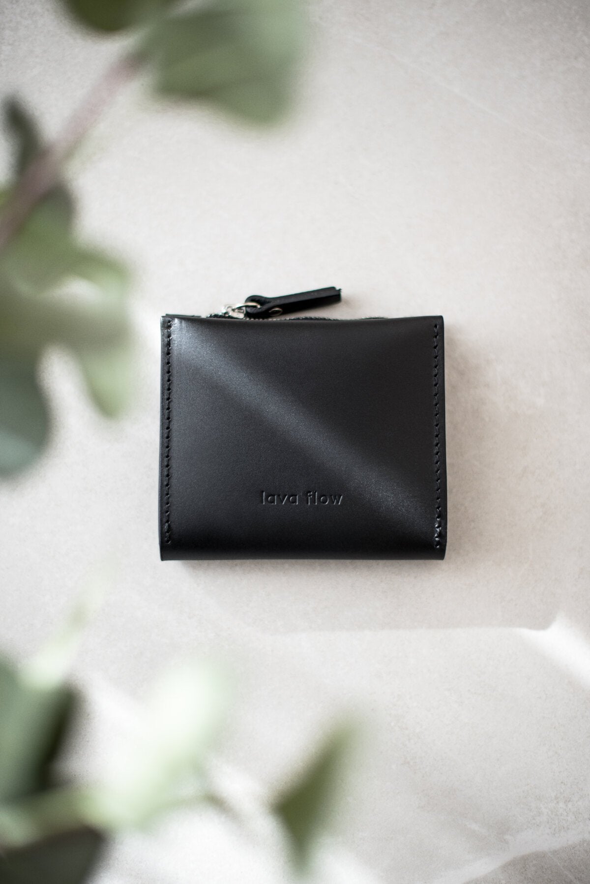 4. Studio shot of Lava flow Classic Leather Wallet MINI TAAL in black on a light surface, showing silver zipper detail