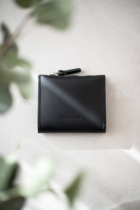 4. Studio shot of Lava flow Classic Leather Wallet MINI TAAL in black on a light surface, showing silver zipper detail