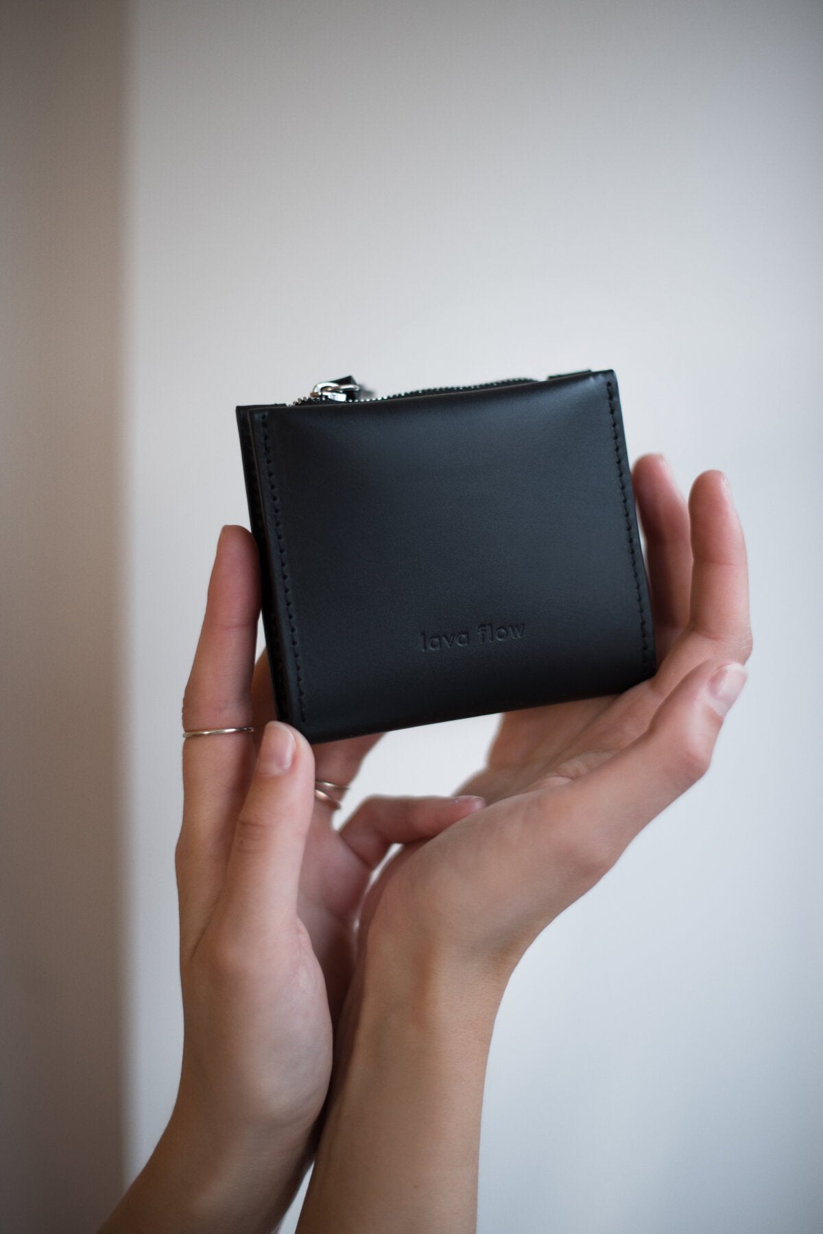 2. Woman displaying Lava flow Classic Leather Wallet MINI TAAL in black, highlighting compact size and sleek style