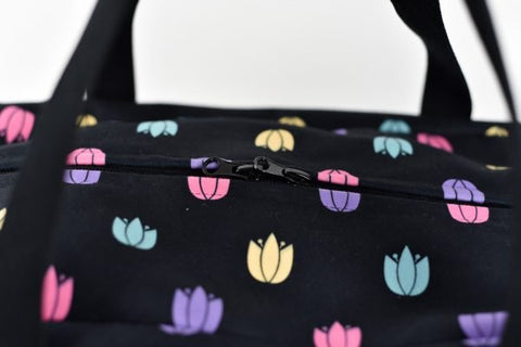 5. Close-up of Garbanota travel bag's zipper and colorful tulip pattern on black polyester fabric