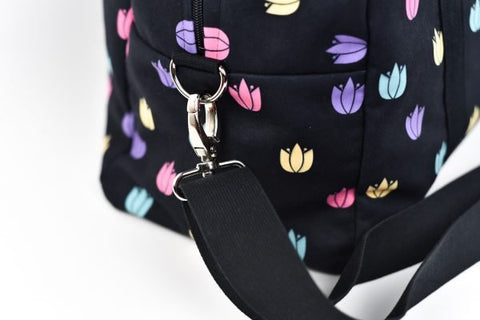 2. Close-up of Garbanota travel bag's detachable strap and colorful tulip pattern on black polyester fabric