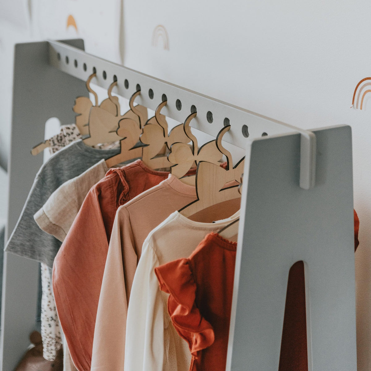 10. Close-up of grey toddler clothing rack with colorful clothes on wooden hangers