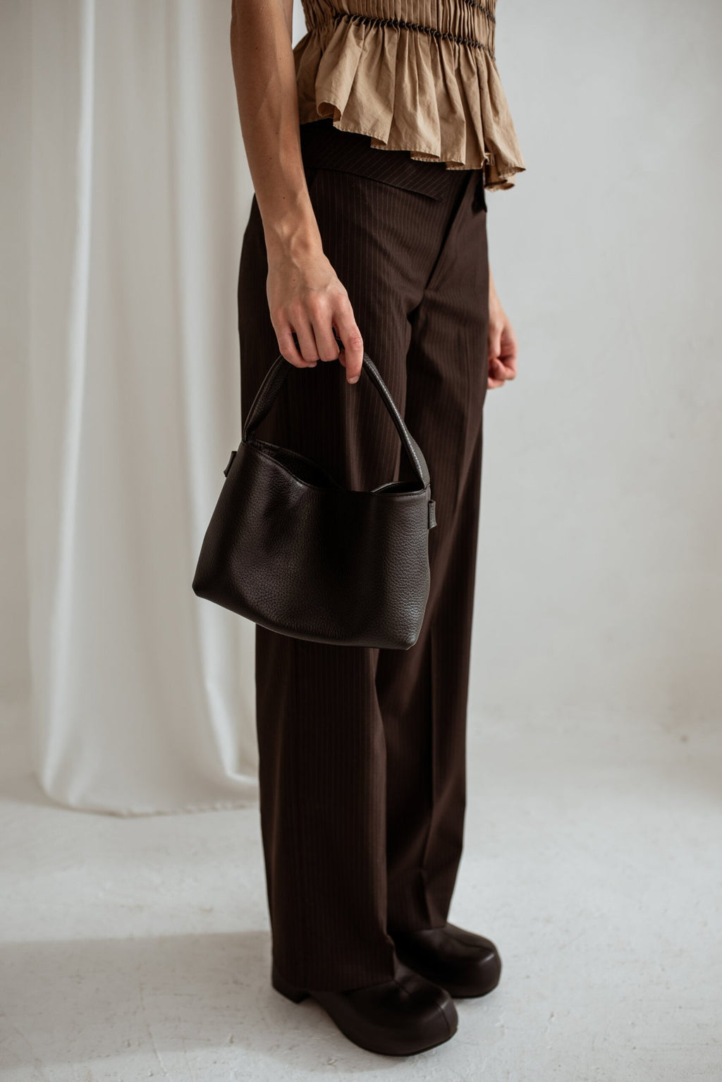 3. Woman standing with Lava Flow Crossbody Bag MERU in black, emphasizing elegant simplicity and functionality