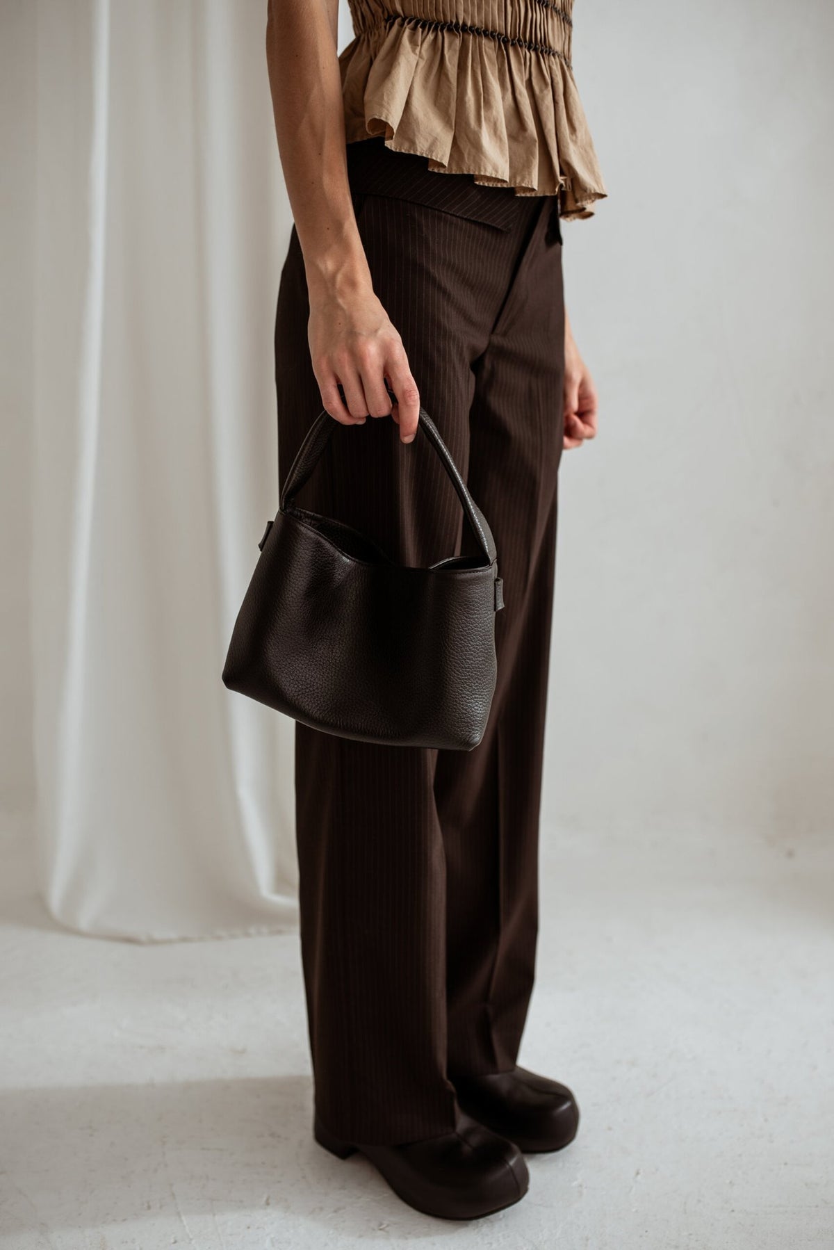 3. Woman standing with Lava Flow Crossbody Bag MERU in black, emphasizing elegant simplicity and functionality