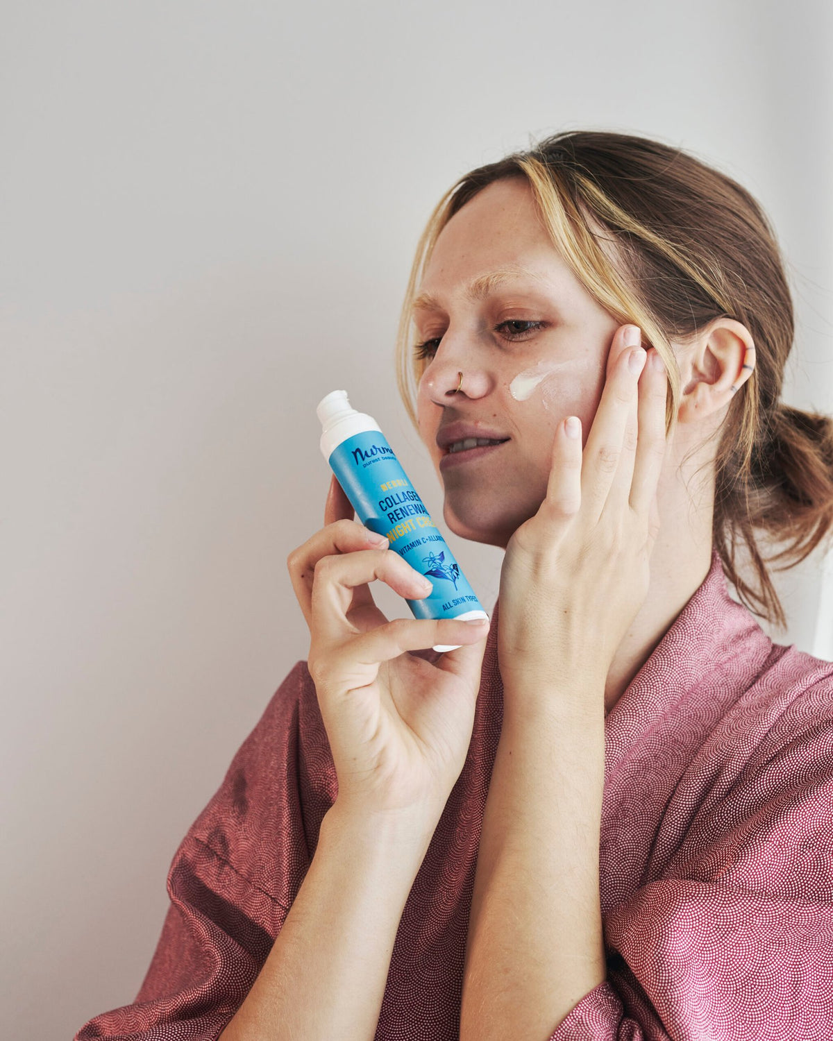 1. Woman applying Nurme Collagen Renewing Neroli Night Cream to her face, showcasing skincare routine