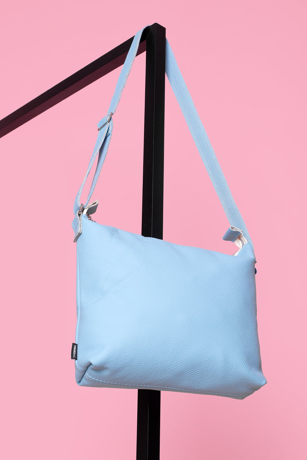 4. Trendbag Anet L shoulder bag in light blue leather hanging on a pink background