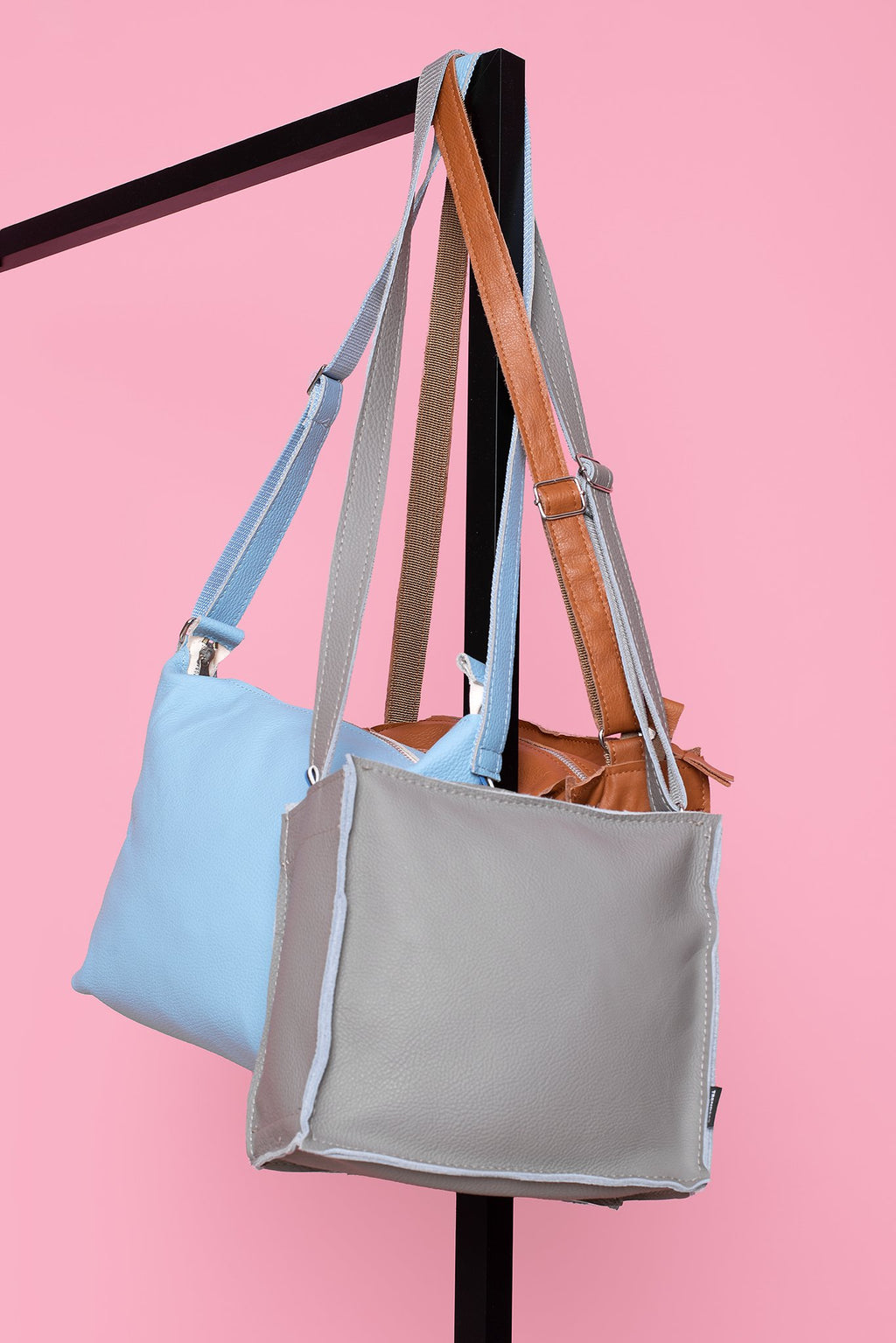 2. Trendbag Folk 1 shoulder bags in peanut, gray, and blue, hanging against a pink backdrop