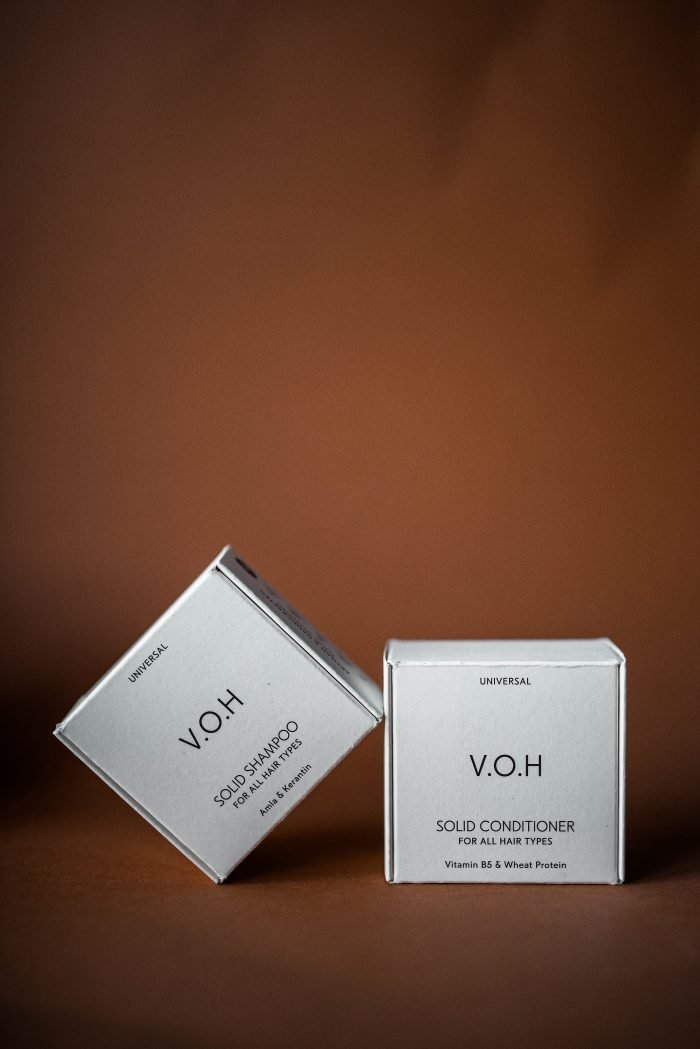 3. Flat lay of V.O.H solid shampoo and conditioner bars on a wooden plate with a hairbrush, emphasizing natural ingredients