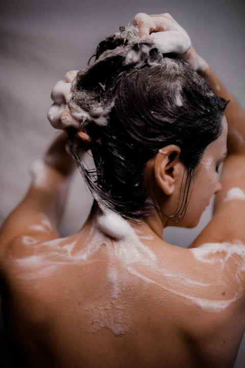 2. Woman applying V.O.H solid shampoo, showing lather and hair care
