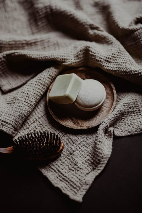 4. V.O.H solid shampoo and conditioner on a wooden plate with a brush, emphasizing natural ingredients